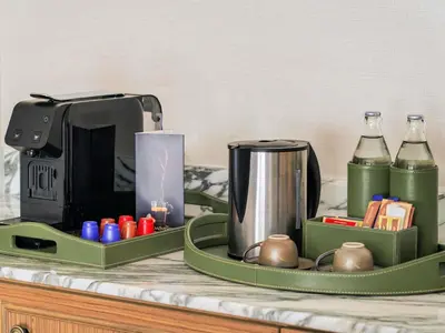 a green tray with a coffee maker and bottles on a counter at Mövenpick BDMS Wellness Resort Bangkok in Bangkok