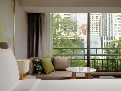 a living room with a couch and a large window at Mövenpick BDMS Wellness Resort Bangkok in Bangkok