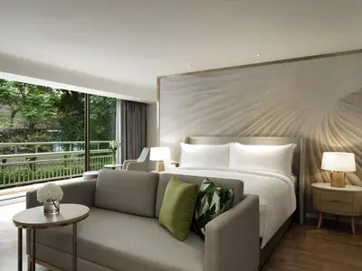 a bedroom with a bed and a couch and a window at Mövenpick BDMS Wellness Resort Bangkok in Bangkok