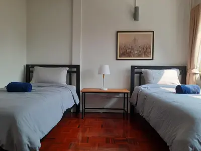 two beds in a room with a table between them at Pingplalee Female House in Bangkok