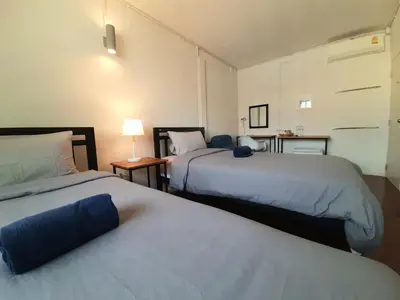 a hotel room with two beds and a table at Pingplalee Female House in Bangkok