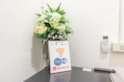 a vase of flowers sitting on a table next to a box at Ze Residence Bang Aor Station in Bangkok
