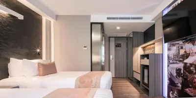 a hotel room with two beds and a tv at Aspira Gems Center Silom in Bangkok
