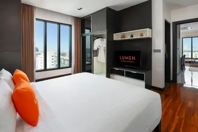 a bedroom with a white bed and a television at Lumen Bangkok Srinakarin in Bangkok