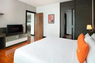 a bedroom with a white bed and a flat screen tv at Lumen Bangkok Srinakarin in Bangkok