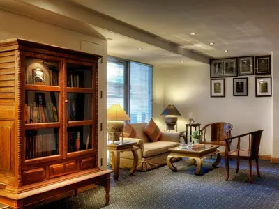 a living room with a couch and a book shelf at Le Siam Hotel Silom Bangkok by PCL in Bangkok