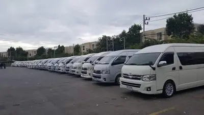 a row of white vans parked in a parking lot at IMPACT Don Mueang Bangkok Guest House in Nonthaburi