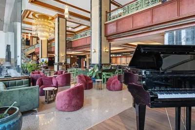 a piano in a lobby with purple chairs and tables at Town in Town Hotel Bangkok in Bangkok