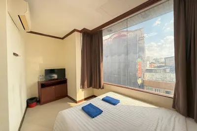 a bedroom with a large window and a bed with blue pillows at Scala Hostel in Bangkok