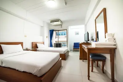 a hotel room with two beds and a desk and a mirror at Siam Palace Hotel in Bangkok