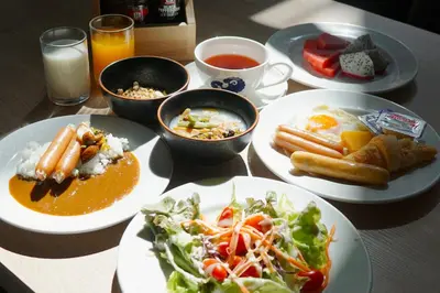 a table with plates of food and bowls of food at Kokotel Bangkok Dheva Thonglor in Bangkok