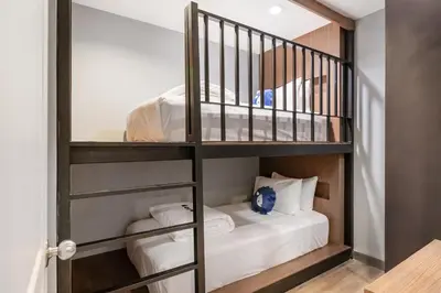a room with a bunk bed with white sheets at Kokotel Bangkok Dheva Thonglor in Bangkok