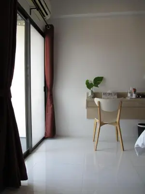 a table and a chair in a room with a window at J.K. Mansion in Bangkok