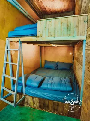 a bunk bed with blue pillows and a ladder at Time Sabai 32 in Bangkok