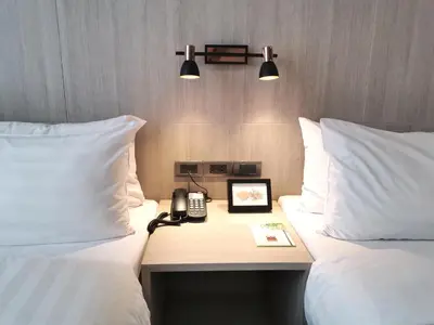 a hotel room with two beds and a desk with a phone at Gold Orchid Bangkok Hotel in Bangkok