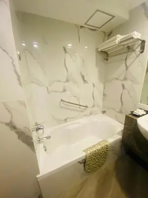 a white bathroom with a tub and a sink at Gold Orchid Bangkok Hotel in Bangkok