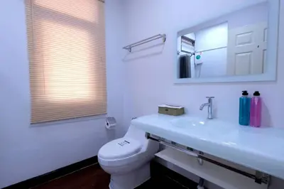 a bathroom with a toilet and a sink and a mirror at 138 White Villa in Bangkok
