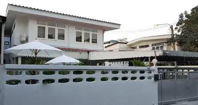 a white fence in front of a house with an umbrella at 138 White Villa in Bangkok