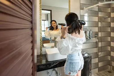 a woman brushing her hair in front of a mirror at Tepbunthom Hostel in Bangkok