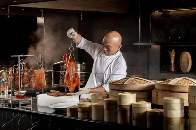 a chef preparing food in a restaurant kitchen at InterContinental Bangkok by IHG in Bangkok
