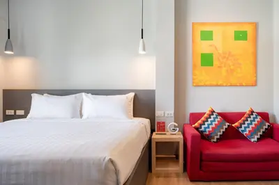a bedroom with a bed and a red chair at iCheck inn Gems Center Silom in Bangkok