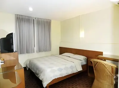 a small bedroom with a bed and a television at Orchid Place in Bangkok