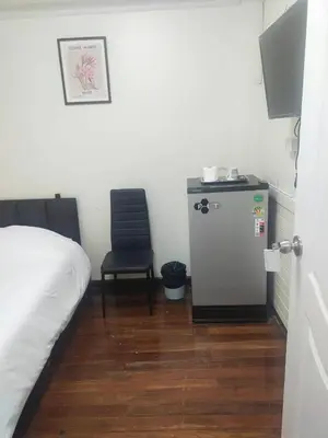 a room with a bed and a chair and a refrigerator at Orchid House in Bangkok