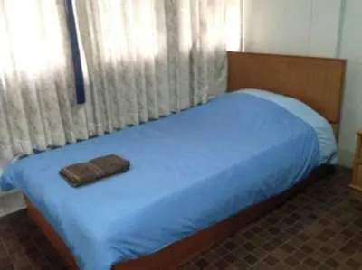 a bedroom with a bed with a blue blanket and curtains at White Orchid Inn I in Bangkok