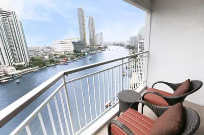 a balcony with two chairs and a view of a river at Shangri-La Bangkok in Bangkok