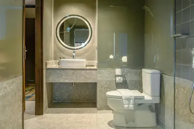 a bathroom with a toilet and a sink and a mirror at Graph Hotels Bangkok in Bangkok