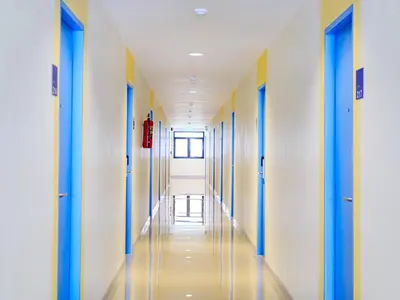an empty corridor of a hospital hallway with blue and yellow doors at HOP INN Chaengwattana in Nonthaburi