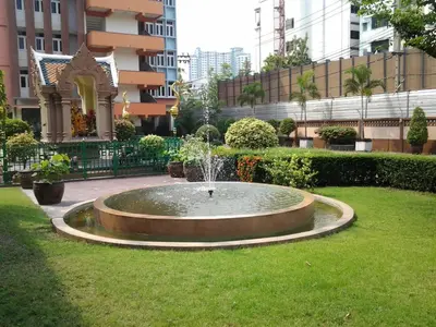 a fountain in the middle of a field of grass at Capital Mansion - SHA Certified in Bangkok