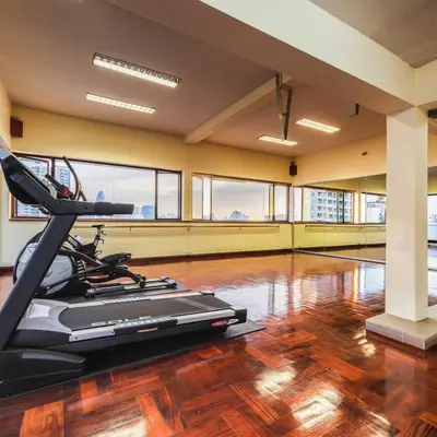 a gym with a treadmill in a room with wood floors at Capital Mansion - SHA Certified in Bangkok