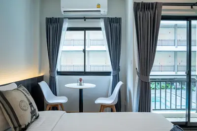 a hotel room with a bed and a table and chairs at College Haus Rangnam in Bangkok