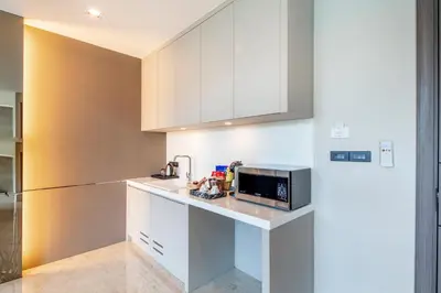 a kitchen with white cabinets and a microwave at The Grand Sala Thai in Bangkok
