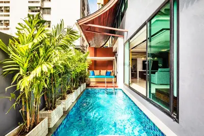 a swimming pool in the middle of a building with plants at The Grand Sala Thai in Bangkok