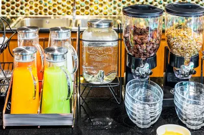 a counter with several jars of orange juice and drinks at The Grand Sala Thai in Bangkok