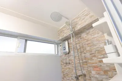 a bathroom with a shower with a stone wall at Baankhon Private room in Thai house Check in by yourself code inbox Adult Only in Bangkok