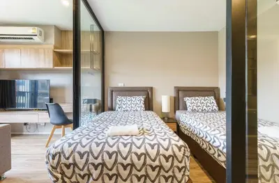 a bedroom with two beds and a desk at Blossom Sathon Condo in Bangkok