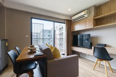 a living room with a couch and a table and a tv at Blossom Sathon Condo in Bangkok