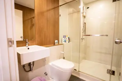 a bathroom with a toilet and a sink and a shower at Blossom Sathon Condo in Bangkok
