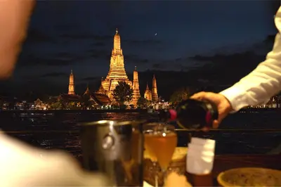 a person pouring a glass of wine in front of a city at The Siam in Bangkok