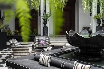a table and chairs with a fountain in front of a house at The Siam in Bangkok