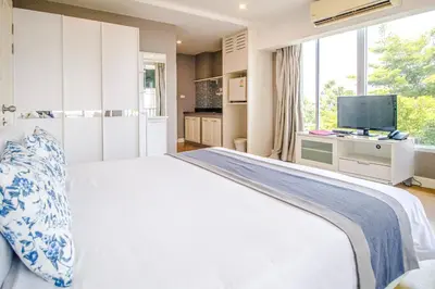a white bedroom with a large bed and a tv at Cinnamon Hotel Bangkok in Bangkok