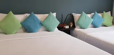 two beds with blue and green pillows in a room at Baan Wangderm Hotel in Bangkok
