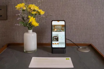 a cell phone sitting on a table next to a vase of flowers at Triple Y Hotel in Bangkok