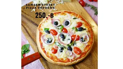 a pizza sitting on top of a wooden cutting board at Samsen Street Hotel in Bangkok