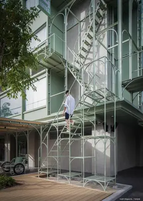 a man walking up the stairs of a building at Samsen Street Hotel in Bangkok