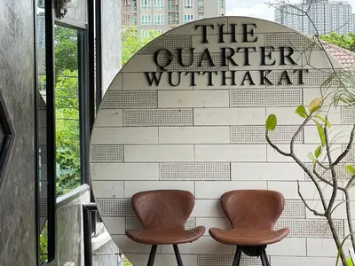 two brown chairs sitting in front of a sign at The Quarter Wutthakat in Bang Khun Thian