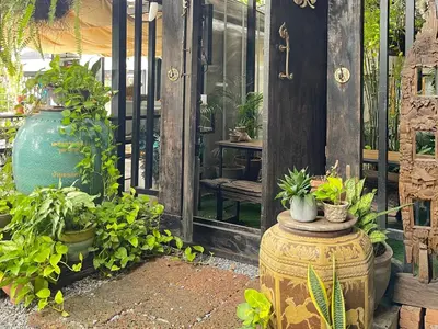 a garden with a large vase and potted plants at The Quarter Wutthakat in Bang Khun Thian
